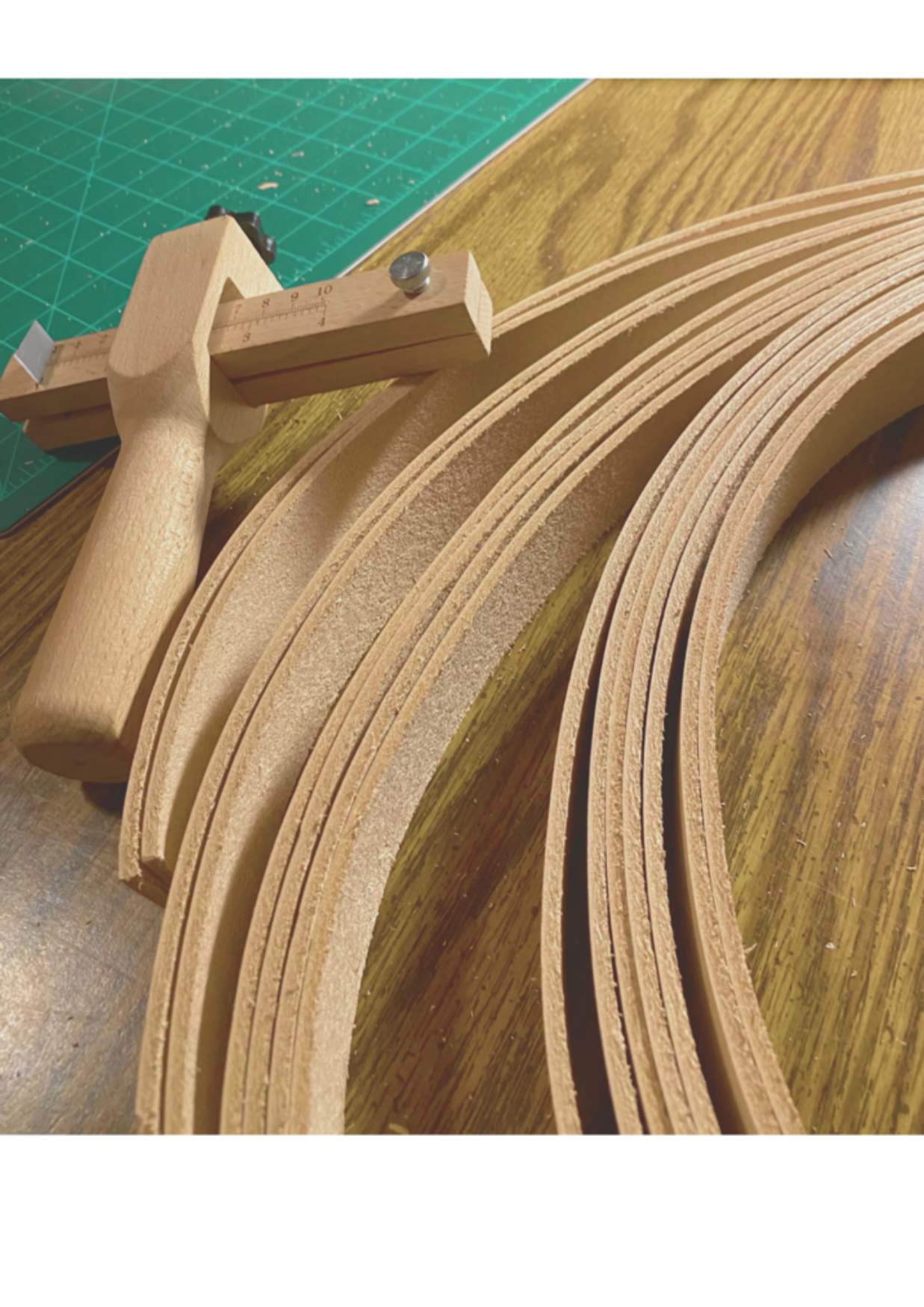 A spiral of uncut leather material next to a leather measuring tool. 